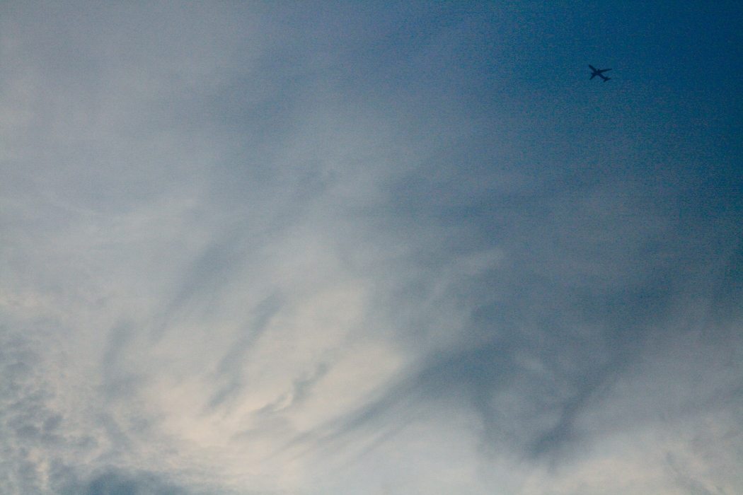 A small airplane flying across a cloudy sky